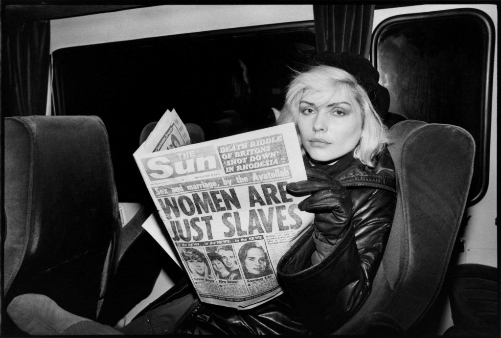Debbie Harry no carro lendo jornal