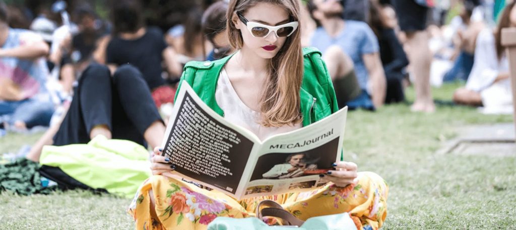 Mulher lê o MECA Journal no MECA Festival